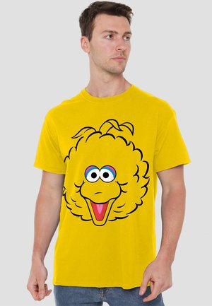 Yellow cotton t-shirt featuring a large cartoon character face design with a fluffy texture, prominent eyes, and a cheerful expression.