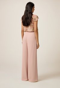 Lichtroze wijde broek met een soepele textuur en een elastische tailleband, gecombineerd met een bloemetjespatroon, kort mouwen top.
