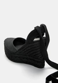 Svart espadrille kilklack sandal med texturerad canvasöverdel, flätad jute mittsula, justerbar rem och öppen tådesign.