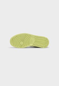 Semelle d'une basket Nike vert clair avec des motifs circulaires et en grille, incluant le logo Nike embossé au centre.