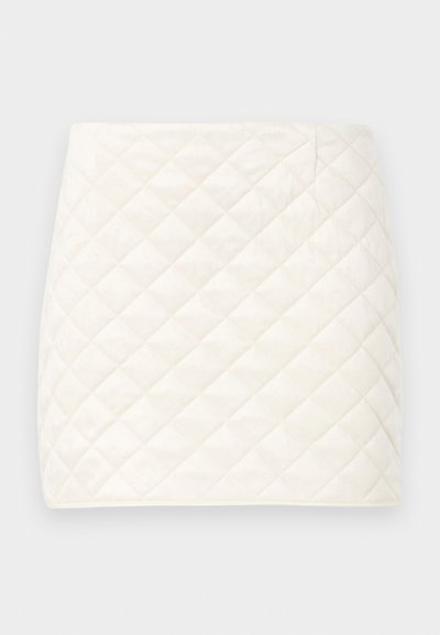 Jupe mini matelassée en tissu blanc doux, avec un motif en diamant et des lignes épurées, dotée d'une texture lisse et sans fermetures visibles.