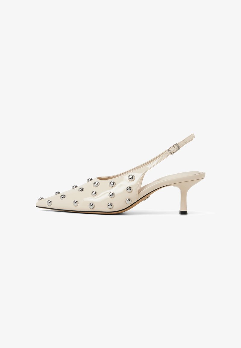 Kiilokärki slingback-korkokengät kiiltävässä kermanvärisessä patenttinanassa, joissa on terävä kärki, koristeltu hopeaisilla niiteillä ja hoikalla korolla.
