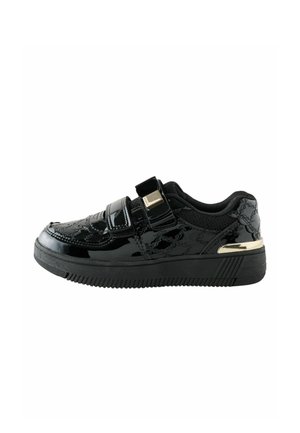Schwarzer Sneaker mit niedrigem Schaft und glänzender Oberfläche, zwei Klettverschlüssen, gemusterten Nähten und goldenem Akzent an der Ferse.