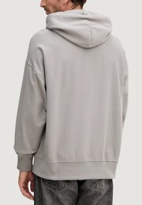 Felpa grigia con cappuccio, vestibilità comoda, polsini a costine e tessuto morbido e strutturato. Presenta una cucitura posteriore e una tasca a marsupio.