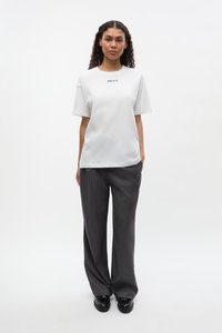 Fehér pamut póló kék "MELTY" grafikával, fekete, vékony csíkozású nadrággal párosítva. Mindkettő laza szabású és sima tapintású.