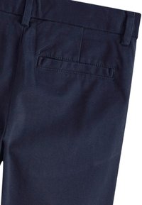 Pantalon bleu foncé avec une poche arrière passepoilée simple et des passants de ceinture sur une taille plate.
