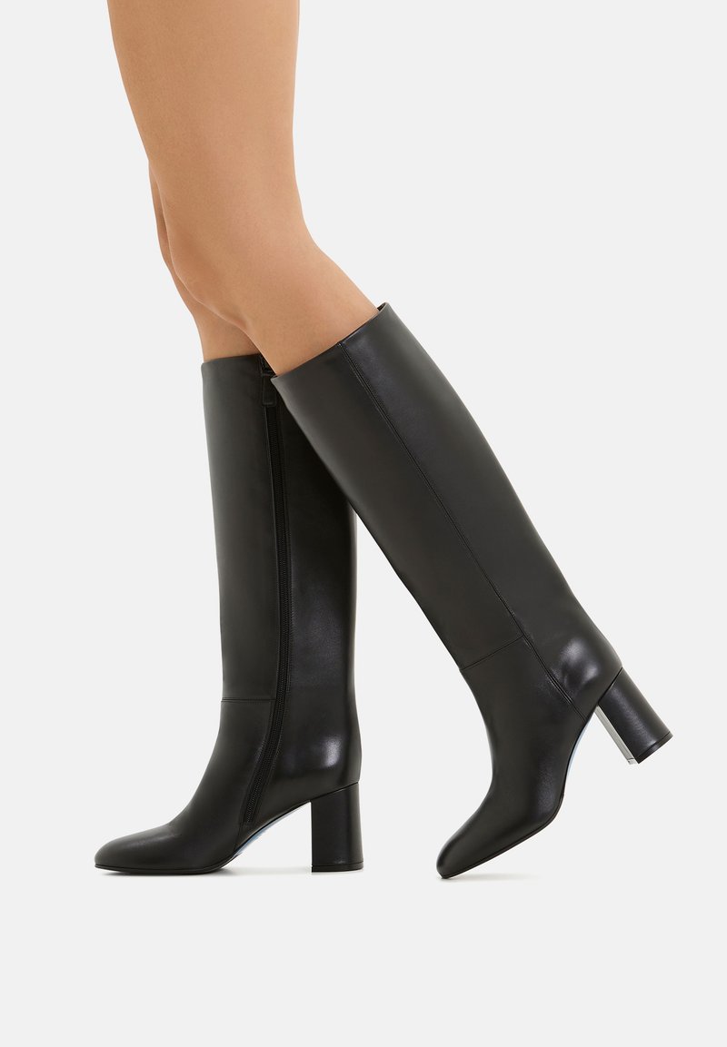 Stivali neri alti fino al ginocchio realizzati in pelle liscia, dotati di una cerniera laterale e di un tacco quadrato. Il design è elegante e aderente.