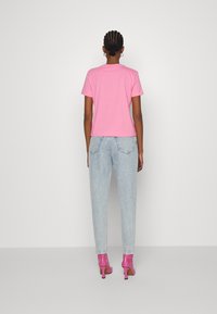 Camiseta rosa de manga corta con un corte relajado, combinada con unos vaqueros de cintura alta de color azul claro y unos zapatos de tacón rosa brillante.