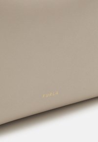 Portafoglio in pelle grigio chiaro con finitura testurizzata, dotato del nome del brand "Furla" in oro stampato sulla parte inferiore.