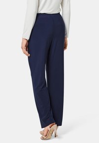 Navy-weite Hosen aus weichem Stoff mit glatter Textur, ausgestattet mit einem dehnbaren Bund und kombiniert mit beigefarbenen Absatzsandalen.