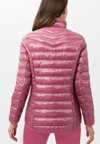 Chaqueta ligera y acolchada en tejido rosa brillante; presenta un cuello alto y costuras horizontales; textura suave con un diseño ajustado.