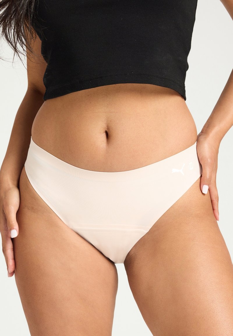 Culottes de bikini haute taille sans coutures Puma en beige clair. Dotées d'un tissu lisse, d'une large ceinture et d'un logo discret sur le côté.
