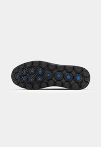 Black rubber shoe sole featuring circular tread patterns with blue accents, providing grip and flexibility.