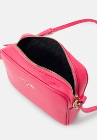 Borsa a tracolla in pelle rosa con chiusura a zip. L'interno presenta una fodera nera a motivi. Dettagli in oro sulla cerniera.