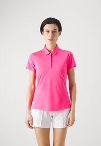 Pink polo shirt lavet af glat stof, med krave, korte ærmer og fem knapper. Båret med hvide shorts.