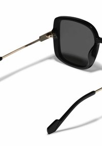 Mustad, ülekaalulised prillid tumedate polariseeritud läätsedega, kuldne metallist riistvara ja mustad templid, millel on sile tekstuur ja nurgeline disain.