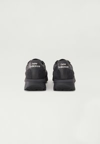 Fekete sportcipők texturált szövet felső résszel, gumitalppal és fehér "new balance" logóval a saroknál. Klasszikus sportos dizájn.
