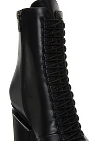 Czarne skórzane botki za kostkę z lace-up po boku i zapięciem na zamek. Charakteryzują się grubym obcasem i gładką teksturą.