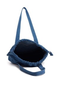 Denim totebag met een gathered opening, donkerblauwe kleur, lange schouderband en een zachte textuur. Het interieur is zwart, wat diepte en ruimte laat zien.