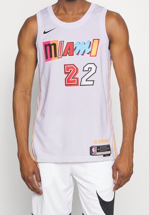 Man wearing white Miami basketball jersey with colorful "MIAMI" text and number 22, paired with white shorts with black Nike swoosh.