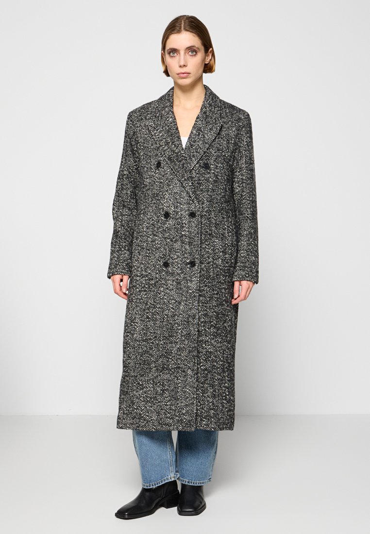 Lange, dubbelzijdige jas in een zwart-wit visgraatmotief, met gelapte revers en zijzakken. Getextureerde wolstof.