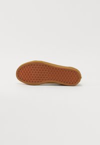 Semelle de chaussure en caoutchouc marron présentant un motif texturé en losanges et un bord surélevé. Le matériau est flexible et a une texture lisse.