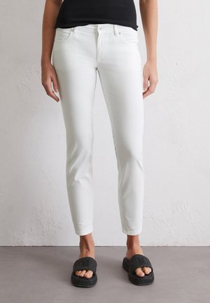 Witte skinny jeans van denim, met een klassiek vijf-pocketdesign, slim fit en een licht vervaagde textuur. Gecombineerd met zwarte instapsandalen.