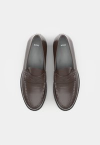 Brune skinn loafers med en glatt finish, med en sydd tåhette og subtile dekorative detaljer. Svart gummisåle.