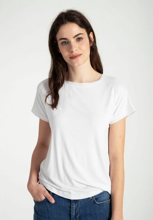 Witte T-shirt met korte mouwen en een ronde halslijn, gemaakt van zacht materiaal, met een losse pasvorm en zichtbare stiksels, gepresenteerd met blauwe denim jeans.