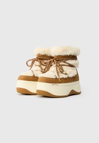 Bruine suède enkelboots met witte nepbont voering, bruine veters en een dikke crèmekleurige plateauzool. Voorzien van een rubberen zool voor grip.