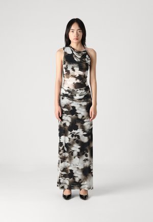 Strakzittende, mouwloze maxi-jurk in zwart-wit bloemenpatroon, met geplooide details rond de halslijn en taille.