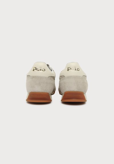 Paire de baskets en daim beige vue de dos, avec les logos "Polo" et "Ralph Lauren" sur les talons, semelles en caoutchouc marron.
