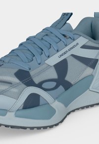 Αθλητικό παπούτσι Under Armour σε ανοιχτό γαλάζιο με διχτυωτό επάνω μέρος, παχιά σόλα και λογότυπα στη πλευρά και στη γλώσσα.