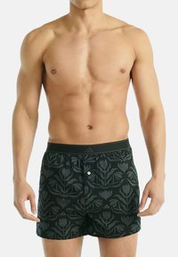 Černé boxerky s květinovým vzorem, elastickým pasem a knoflíkovým detailem na přední straně, vyrobené z lehkého materiálu.