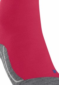 Calzino rosa solidale con texture a costine, tallone e punta grigi, caratterizzato da cuciture bianche e un piccolo logo blu vicino alla parte superiore.
