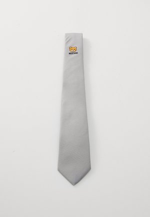 Harmaa silkki-solmio, jossa on tekstuuri ja karhun logo sekä "Moschino"-teksti kapean pään lähellä.