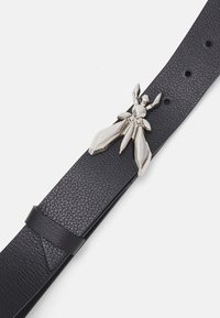 Cintura in pelle nera con una fibbia metallica a forma di insetto con dettagli angolari. Superficie testurizzata con cinque fori per la regolazione.