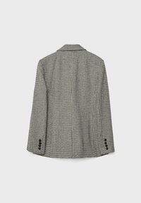 Blazer à carreaux noir et blanc, avec un col cranté, des manches longues et trois accents de boutons sur chaque manche. Tissu texturé.