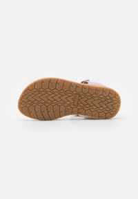 Podeszwa buta z teksturowanym wzorem, z jasnobrązowym gumowym podkładem oraz uformowanym bieżnikiem dla lepszego chwytu. Projekt jest funkcjonalny i trwały.