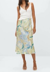 Pestrá mramorovaná midi sukně v zelené, modré a béžové barvě, vyrobená z lehkého materiálu, v kombinaci s přiléhavým bílým tílkem.