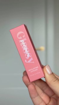 Emballage rectangulaire rose pour le gloss à lèvres Ink Glasting, avec du texte blanc et une capacité de 4,5 ml, tenu dans une main.