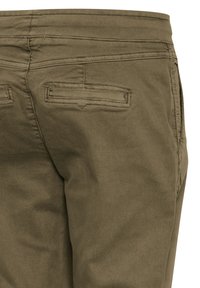 Pantalon vert olive avec une texture lisse, doté de deux poches arrière et de coutures décoratives. La taille est droite et se détache du corps.