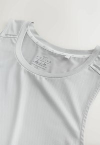 Hellgraues aktives Tanktop aus strukturiertem Stoff mit rundem Ausschnitt, ohne Ärmel und reflektierenden Details an den Schultern.