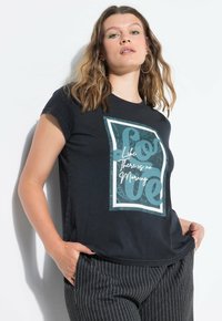 Camiseta de algodón negra con un gráfico de patrón paisley que incluye el texto "Ama la vida, no hay mañana". Cuello redondo y mangas cortas.