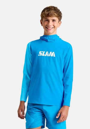 Teen boy wearing bright blue long-sleeve shirt with "SLAM" logo and matching shorts, smiling against a plain background.