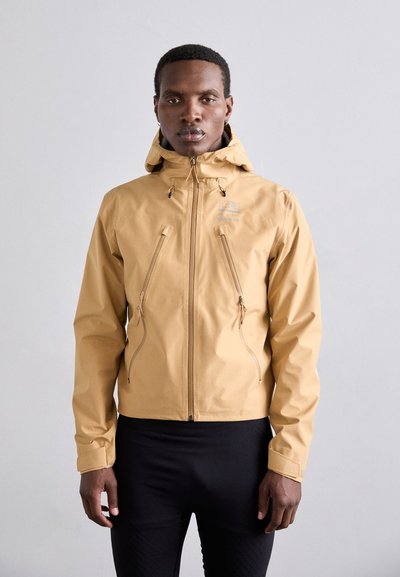 Khakifarbene wasserdichte Jacke mit Kapuze, ausgestattet mit zwei Reißverschlusstaschen und verstellbaren Manschetten. Glatte Textur und leichtes Material.