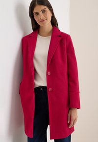 Fuchsia wolblend jas met een opgestikte kraag, drie knopen, zijzakken en een rechte silhouet, gedragen over een lichtbeige top.