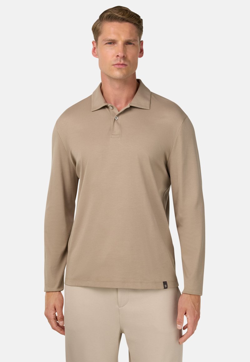 Polo a maniche lunghe beige realizzato in tessuto liscio, con colletto classico, pattina con bottoni e un sottile etichetta con logo vicino all'orlo.