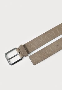 Grå mocka bälte med en rektangulär svart metallspänne som har präglad logotyp, platt struktur och jämn textur. Justerbar längd.