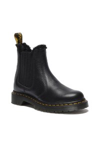 Botín chelsea de cuero negro con superficie texturizada, paneles elásticos en los laterales, suave forro de piel de pelo, costuras amarillas y suela de goma gruesa.
